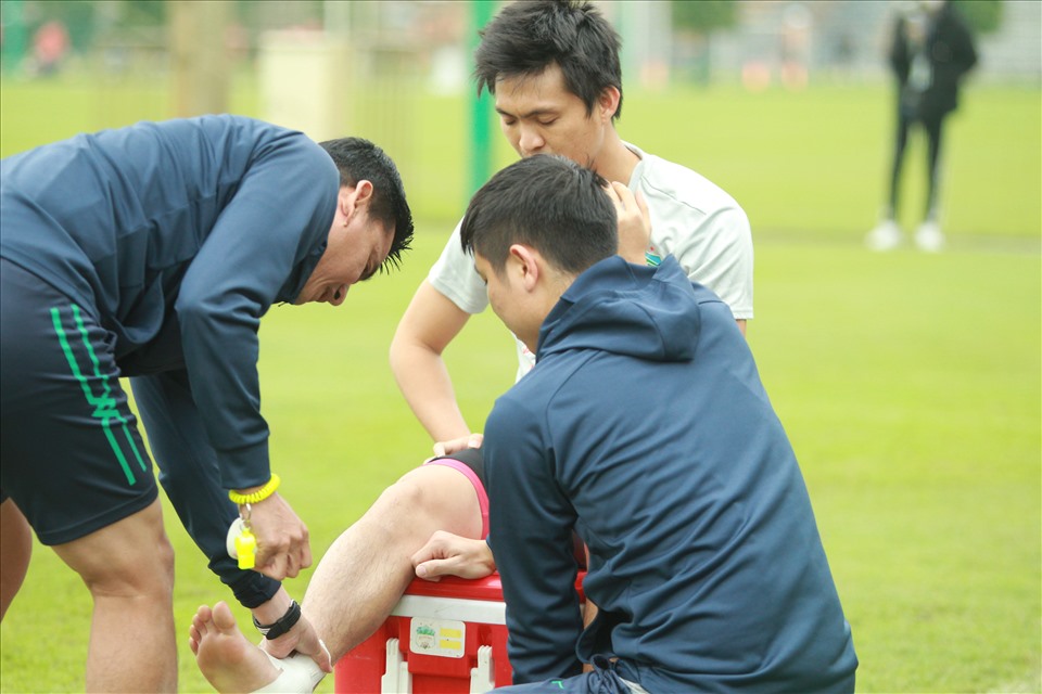Huấn luyện viên Kiatisak hỗ trợ bác sĩ băng bó chân cho Tuấn Anh. Ảnh: P.T