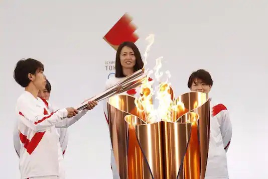 Người cầm đuốc là Azusa Iwashimizu - một thành viên của đội tuyển bóng đá nữ quốc gia Nhật Bản - thắp sáng ngọn đuốc Olympic Tokyo trong ngày rước đuốc đầu tiên ở Naraha, tỉnh Fukushima. Ảnh: AFP