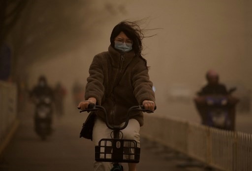 Người dân gặp khó khăn khi di chuyển trong điều kiện cát bụi dày đặc. Ảnh: AFP