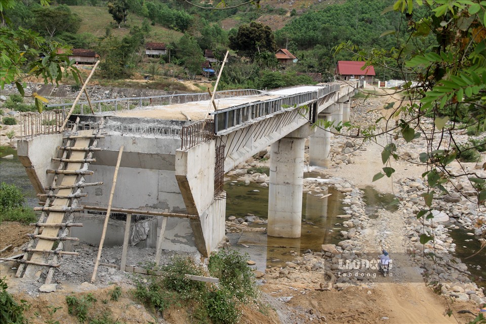 Cách UBND xã Vĩnh Kim chừng 4 km, thôn O3 nằm ngay dưới hạ lưu chân đập Nhà máy Thủy điện Vĩnh Sơn 5. Qua ghi nhận, cây cầu nối làng O3 nối với trung tâm xã Vĩnh Kim dù đã hoàn thành việc đổ trụ cầu, đúc dầm, nhưng đơn vị thi công chỉ mới đổ sàn 2/5 nhịp của cây cầu. Ảnh: N.T