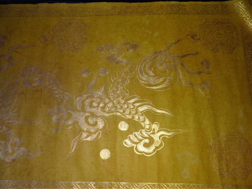 Bên cạnh giấy Dó các loại, bà Tân cũng lữu giữ một vài “phiên bản” đặc biệt mà ít khi bà đem ra. Giấy gió màu vàng, với hoa văn rồng chìm thời Nguyễn được vẽ bằng tay.