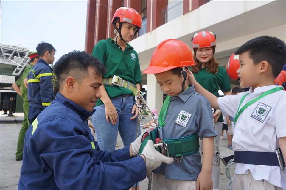 Trước khi khóa học bắt đầu, các chiến sĩ PCCC tiến hành cho các em học sinh đội mũ, mặc đồ bảo hộ.