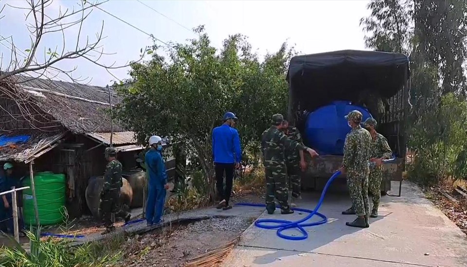 Lực lượng vũ trang tỉnh Kiên Giang mang nước ngọt đến tận nhà cho các hộ dân bị thiếu nước do hạn mặn ở huyện biên giới Giang Thành. Ảnh: PV