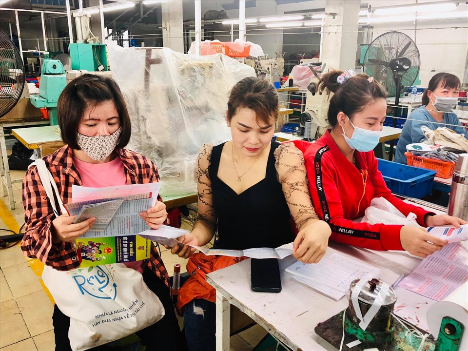 Công nhân lao động tìm hiểu thông qua tờ rơi tuyên truyền cuộc bầu cử đại biểu Quốc hội, HĐND các cấp. Ảnh BTG