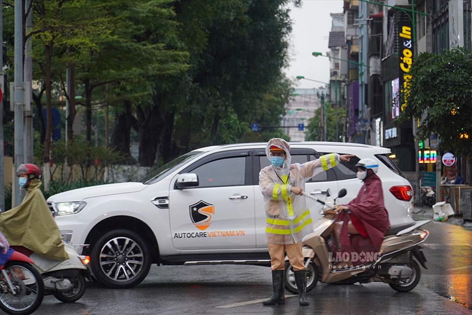 Lực lượng cảnh sát giao thông đứng phân luồng giao thông dưới trời mưa.