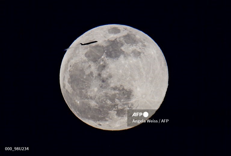 Một máy bay bay qua siêu trăng. Ảnh: AFP