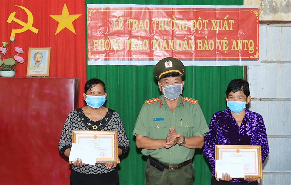 Thừa ủy quyền đại tá Đinh Văn Nơi, Giám đốc Công an tỉnh An Giang, đại tá Mai Văn Nói, Trưởng phòng Xây đựng phong trào bảo vệ an ninh Tổ quốc trao Giấy khen cho 2 phụ nữ người Khmer. Ảnh: Vũ Tiến