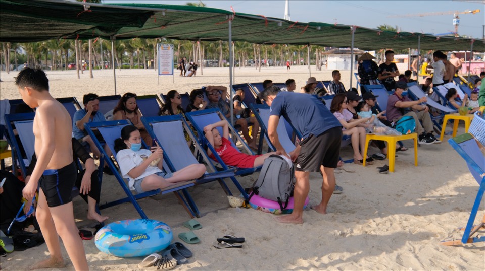 Nhiều nhóm khách ngồi chơi trên bãi biển khu du lich Bãi Cháy, thành phố Hạ Long (Quảng Ninh) không thực hiện đeo khẩu trang (hoặc đeo chiếu lệ) theo khuyến cáo của chính quyền địa phương. Ảnh: T.N.D
