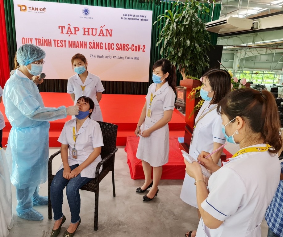 Cán bộ CDC Thái Bình hướng dẫn đội ngũ y tế của Tân Đệ quy trình lấy mẫu test nhanh sàng lọc SARS-CoV-2.