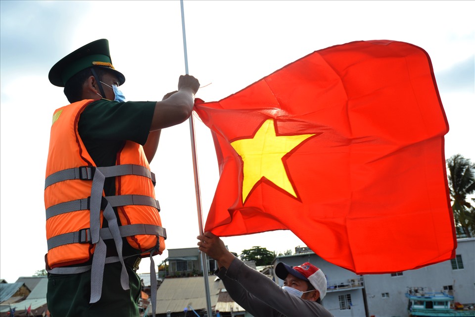 Việc tặng cờ Tổ quốc và ảnh Bác Hồ cho ngư dân được lực lượng Biên phòng tổ chức theo nghi thức trang cả về cách trao cũng như cách thượng kỳ. Ảnh: LT