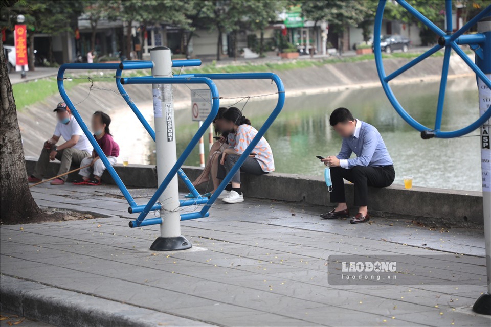Nhiều người không đeo khẩu trang, vô tư ngồi nói chuyện tại khu vực hồ Ngọc Khánh, phường Ngọc Khánh, quận Ba Đình.
