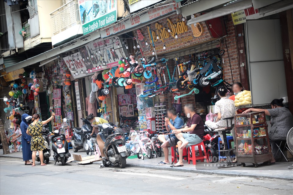 Nhiều người dân không tuân thủ việc đeo khẩu trang, ngồi bán hàng trên vỉa hè đường Lương Văn Can, quận Hoàn Kiếm.