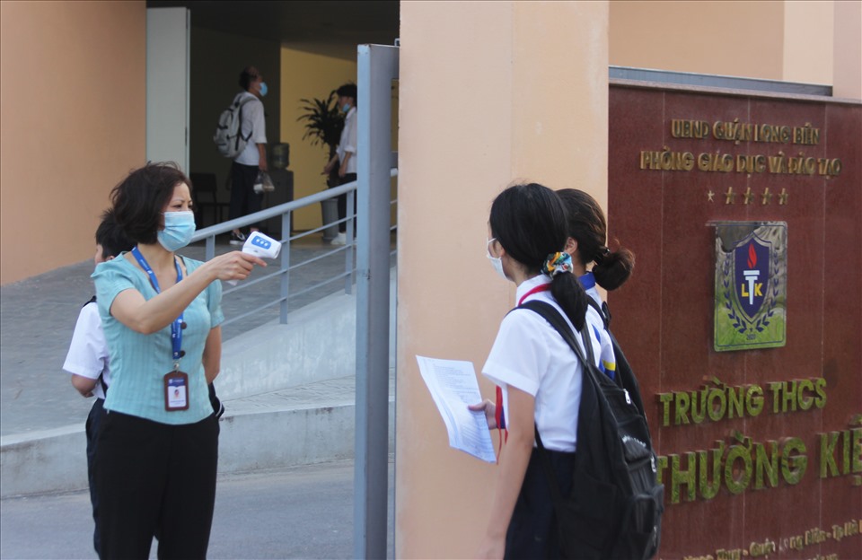 Giáo viên và cán bộ nhà trường thực hiện kiểm tra thân nhiệt cho học sinh trước khi vào trường
