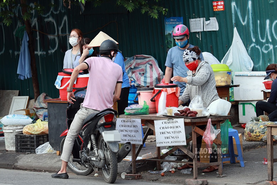 Tại phố Nguyễn Quốc Trị (Cầu Giấy, Hà Nội) những hàng dài hàng quán bán đồ ăn sáng như bánh mỳ, xôi,... vẫn đang được bày bán công khai. Mặc dù, người bán và người mua đều đeo khẩu trang nhưng tại những điểm này vẫn tiềm ẩn những nguy cơ lây lan dịch bệnh.