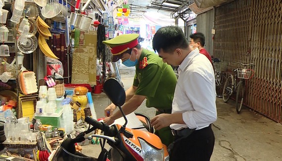 Công an phường Vân Giang lập biên bản xử lý các trường hợp không đeo khẩu trang tại khu vực Chợ Rồng Ninh Bình. Ảnh: NT