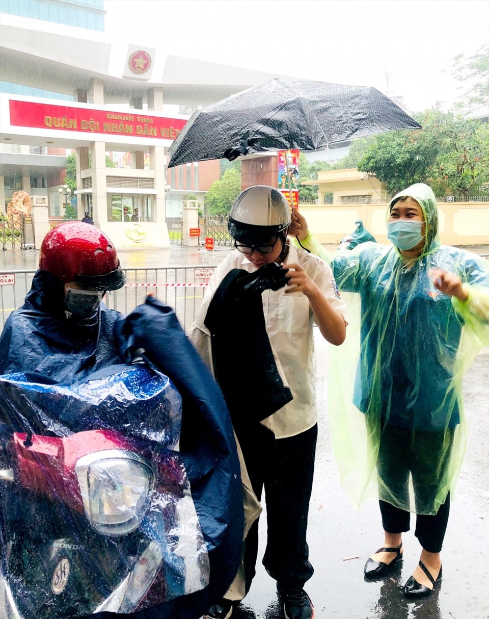 Thanh niên tình nguyện quận Ba Đình đón thí sinh dưới trời mưa to. Ảnh: Ngọc Minh