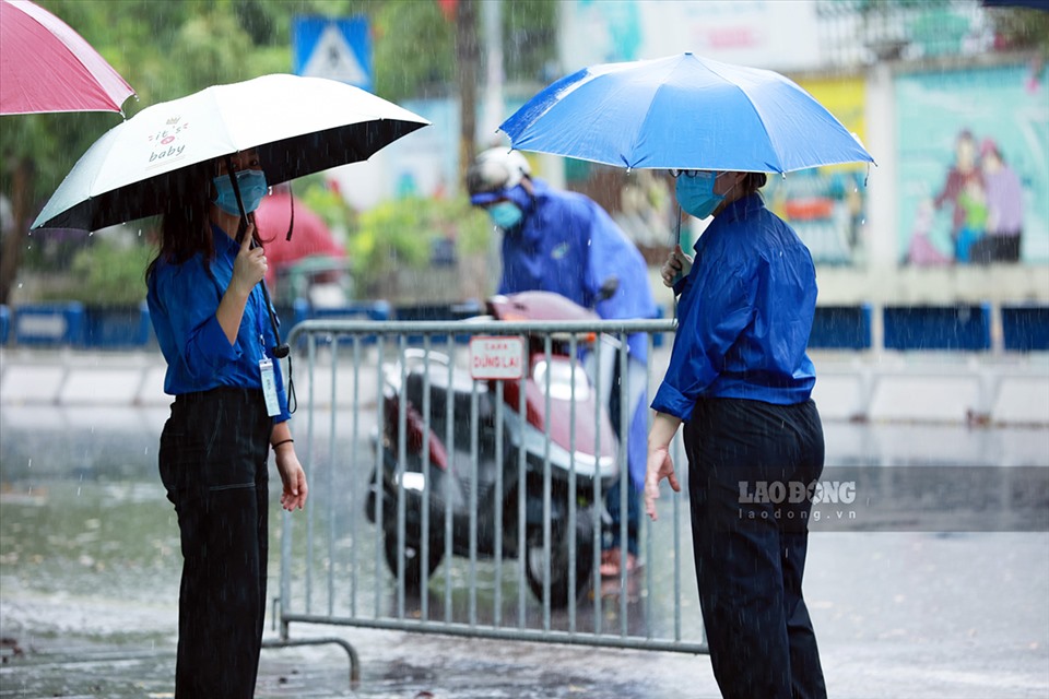 Bất chấp trời mưa, thân người ướt sũng, đội ngũ tình nguyện viên vẫn sẵn sàng để đón các em học sinh vào địa điểm thi an toàn. Ảnh: Hải Nguyễn