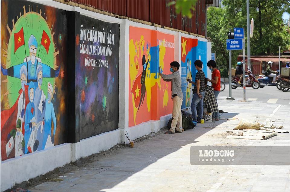 Những bức tranh cổ động đang được các họa sĩ miệt mài vẽ lên trên bức tường ở đường Vũ Trọng Khánh (Hà Đông, Hà Nội) mấy ngày vừa qua đã thu hút sự chú ý của người đi đường.
