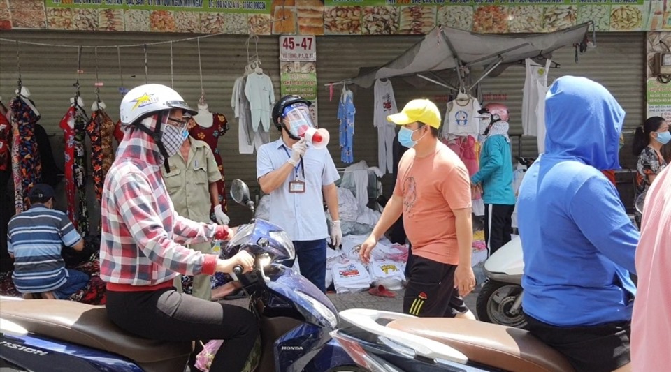 Cơ quan chức năng dùng loa để tuyên truyền, hướng dẫn các tiểu thương dọn dẹp sạp hàng và yêu cầu người dân đi chợ mua hàng không tụ tập đông người. Ảnh: Huyên Nguyễn