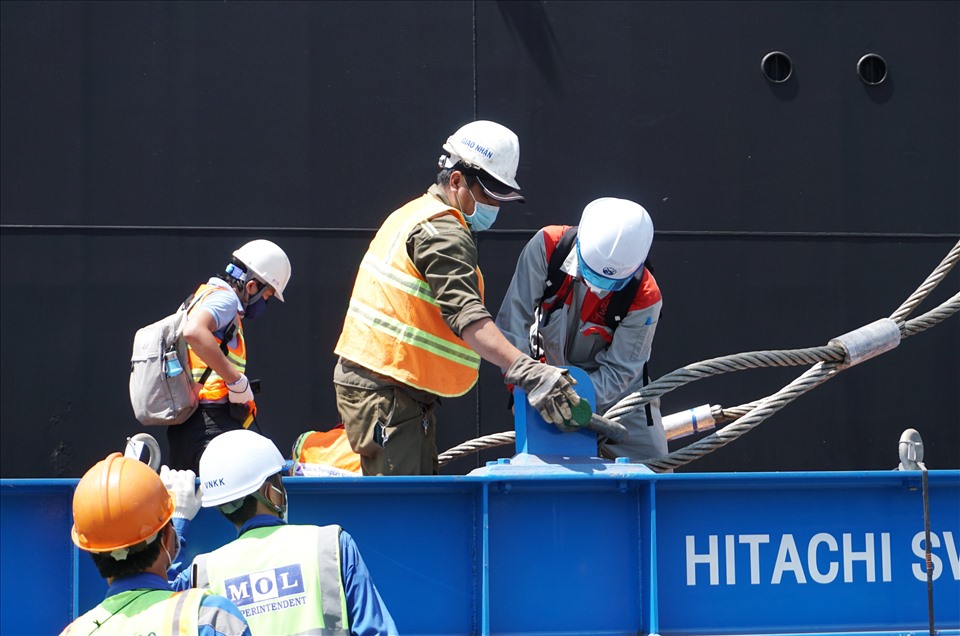 Các chuyên gia, công nhân thực hiện nối cáp vào khung để cẩu toa xe khỏi tàu vận chuyển Pulang Tala.