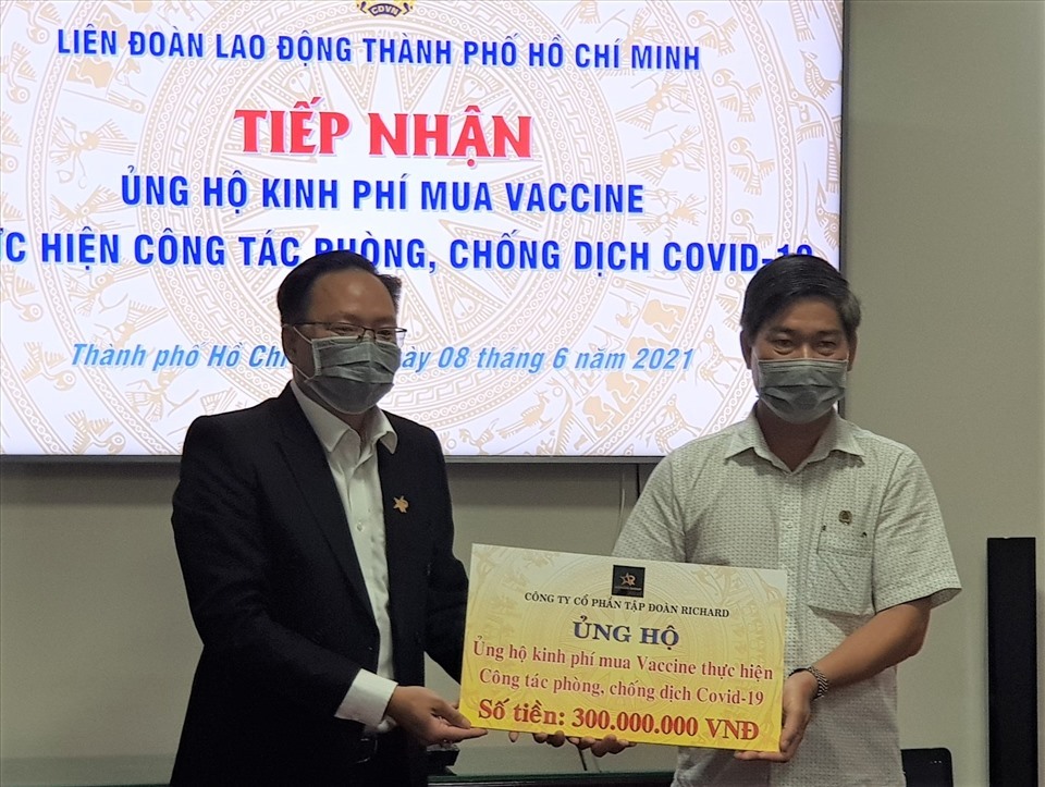 Đại diện Công ty Cổ phần Tập đoàn Richard (bên trái) trao biểu trưng hỗ trợ 300 triệu đồng để mua vaccine phòng COVID-19 cho người lao động. Ảnh Đức Long