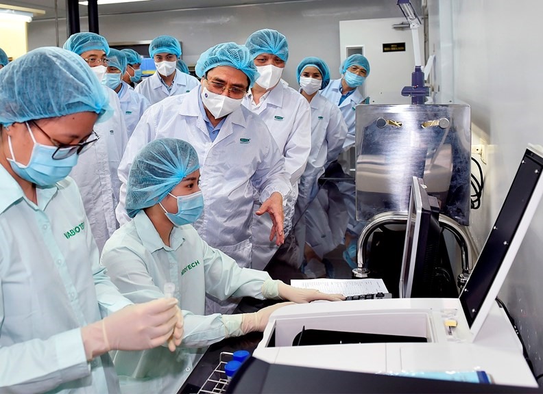 Thủ tướng Phạm Minh Chính thăm hỏi, động viên các nhà khoa học đang làm việc tại Viện Vệ sinh dịch tễ Trung ương và Công ty VABIOTECH. - Ảnh: VGP