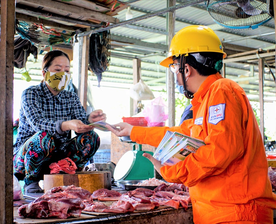 Nhân viên của EVNSPC tuyên truyền sử dụng điện an toàn, tiết kiệm tại một khu chợ ở Thành phố Châu Đốc, tỉnh Anh Giang trong mùa dịch. Ảnh EVNSPC cung cấp.