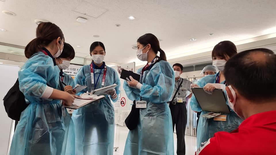 Các tình nguyện viên tại Nhật Bản hỗ trợ đoàn thể thao Việt Nam sau khi nhập cảnh. Các thành viên sẽ phải cài đặt phần mềm theo dõi sức khỏe OCHA, theo quy định của ban tổ chức. Ảnh: Thu Sâm