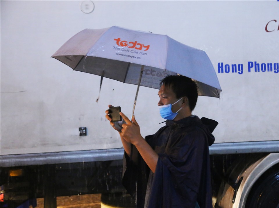 Giữa con mưa nặng hạt, một thành viên các tổ công tác, đang cố gắng ghi hình các dòng phương tiện đổ vào thành phố.