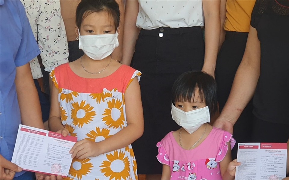 Hai cháu nhỏ con của công nhân Đào Thị Sim nhận sổ tiết kiệm. Ảnh: T.D