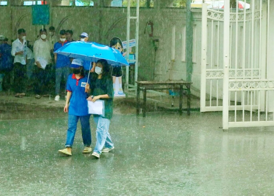 Các bạn tình nguyện viên mang ô đón các thí sinh vào phòng thi. Ảnh: T.T