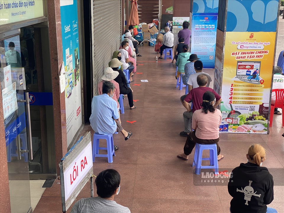 Ghi nhận sáng ngày 9.7, tại Co.op Mart Nhiêu Lộc (Quận 3), người dân đi mua sắm  theo phiếu ngày lẻ được bố trí ngồi chờ đợi và giữ khoảng cách.