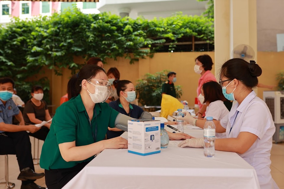 Cán bộ y tế khám sàng lọc cho người dân trước khi tiêm vaccine COVID-19 ở Hà Nội. Ảnh: Hải Nguyễn
