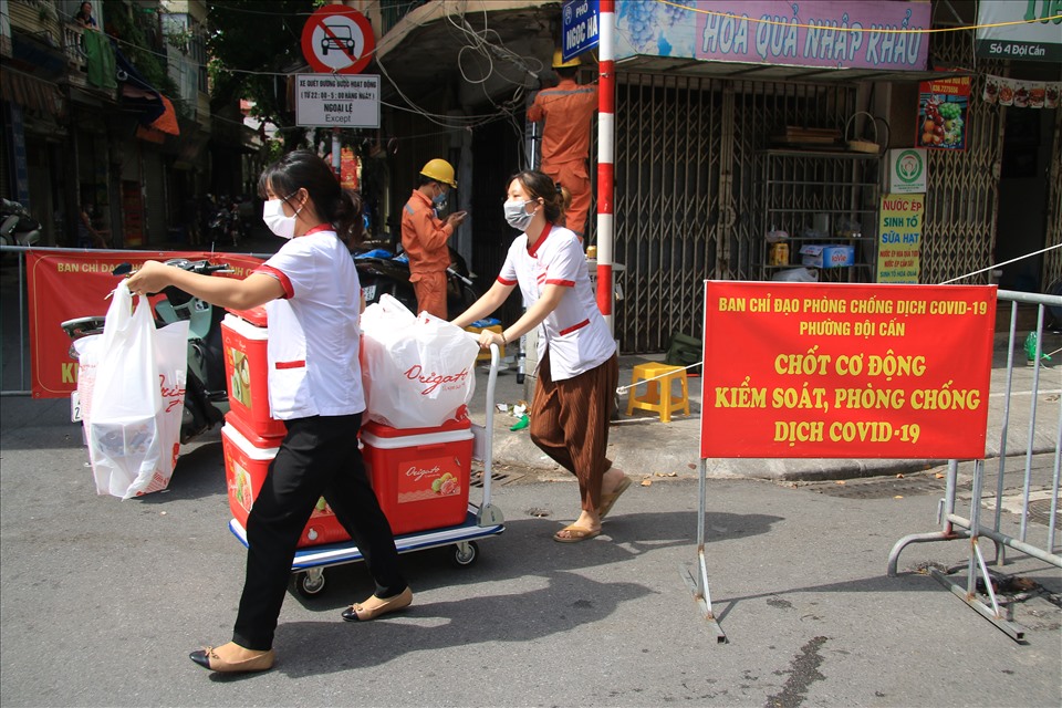 Nhân viên một cửa hàng bánh gần khu vực phong toả dọn dẹp đồ đạc và đóng cửa quán.