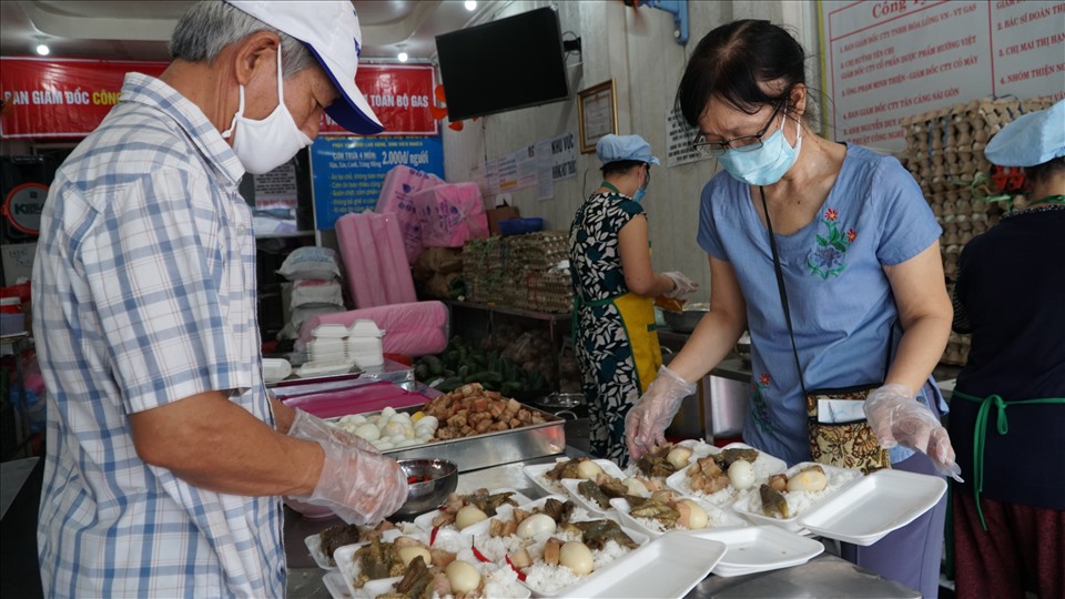 Chú Thảo và cô Huệ cẩn thận chuẩn bị những phần cơm từ nguồn tài trợ của chương trình “Sài Gòn ơi, đừng bỏ bữa”
