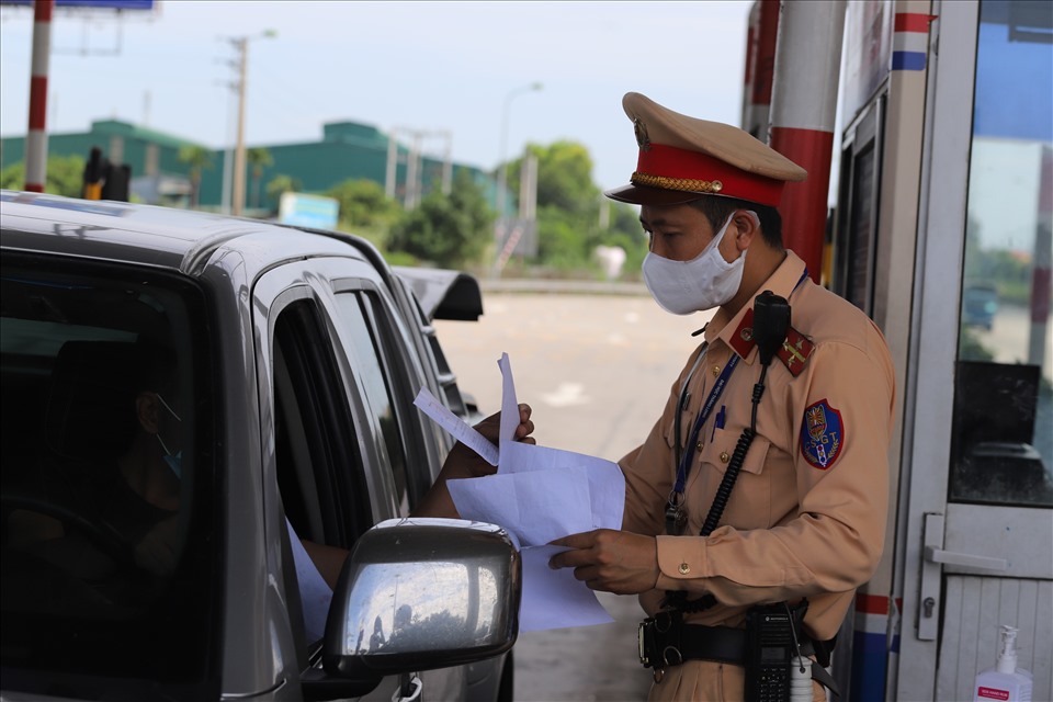 Cảnh sát giao thông kiểm tra giấy tờ và hướng dẫn tài xế vào khu vực khai báo tại chốt Pháp Vân - Cầu Giẽ. Ảnh: P.Đ