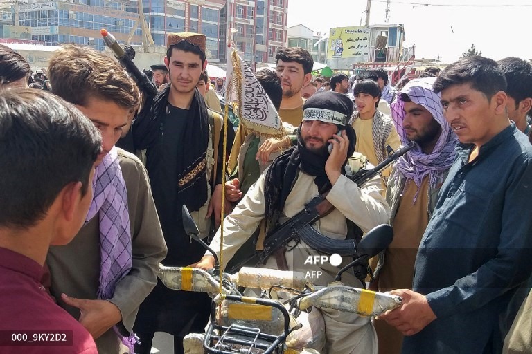 Người dân Afghanistan đứng quanh tay súng Taliban (giữa) tại Pul-e-Khumri vào ngày 11.8 sau khi Taliban chiếm được Pul-e-Khumri, thủ phủ tỉnh Baghlan, cách Kabul khoảng 200 km về phía bắc. Ảnh: AFP