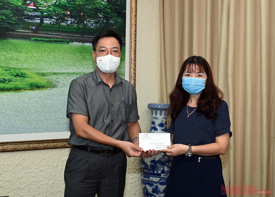 Đồng chí Phan Huy Thắng, Trưởng Ban thư ký Biên tập Báo Nhân Dân trao quà hỗ trợ của các cựu sinh viên khoa Báo chí cho đại diện nhà trường.