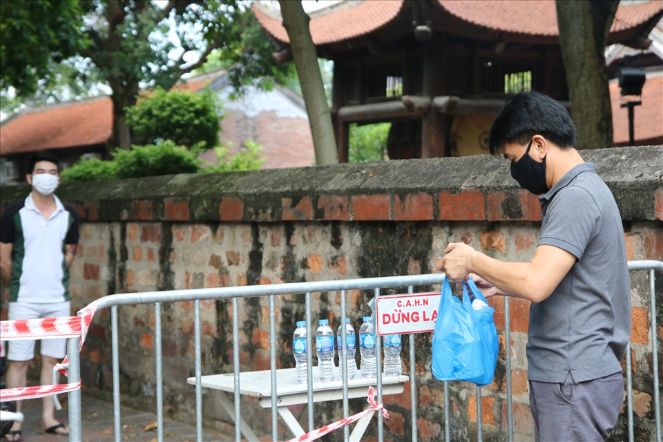 Người dân tiếp tế hàng hoá, lương thực vào phía bên trong phường Văn Miếu - nơi đang thực hiện cách ly y tế ở Hà Nội. Ảnh T.Vương