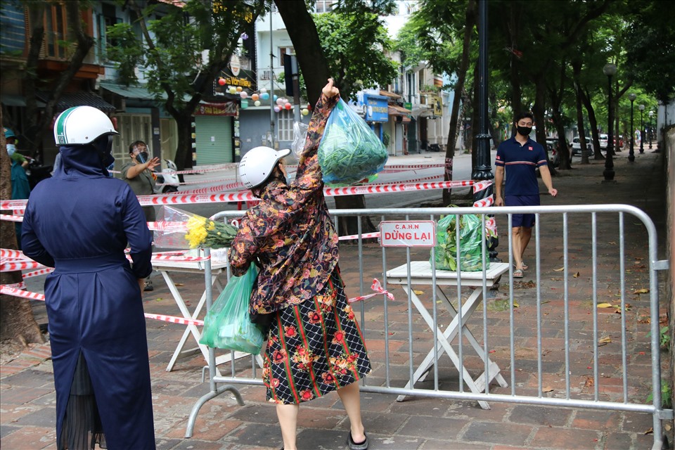 Người dân tiếp tế hàng hoá, lương thực vào phía bên trong phường Văn Miếu - nơi đang thực hiện cách ly y tế ở Hà Nội. Ảnh T.Vương