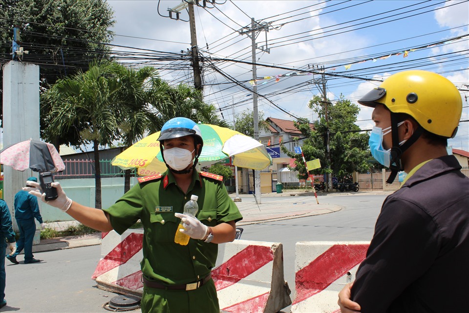 Công an pử phường Thuận Giao hướng dẫn cho người dân còn di chuyển ở ngoài đường về việc tuân thủ giãn cách trong thời gian thực hiện “khóa chặt“.