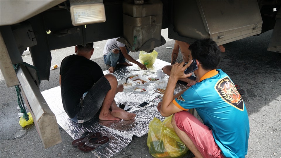 Trời nắng nóng, rồi lại mưa to gió lớn; cánh tài xế phải bày biện để dùng bữa dưới gầm xe tải.