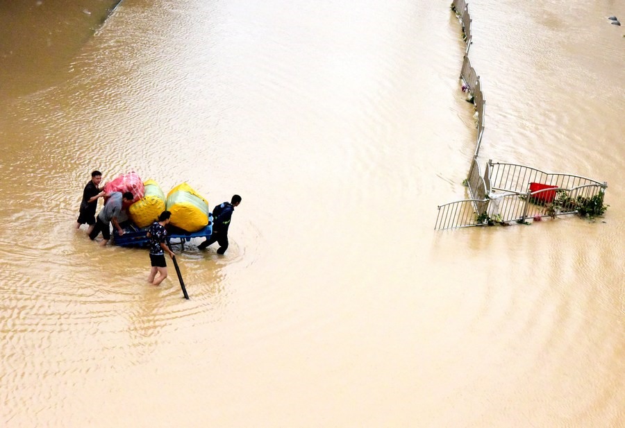 Người dân vận chuyển tài sản trên một con phố ngập lụt ở Trịnh Châu, tỉnh Hà Nam, miền trung Trung Quốc, ngày 21.7.2021. Ảnh: Tân Hoa Xã