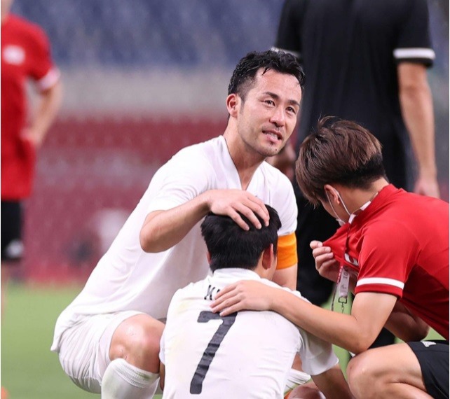 Đội trưởng Maya Yoshida đến an ủi đàn em, nhưng chính anh cũng thể giấu được cảm xúc, bật khóc nức nở. Yoshida cũng là người đeo băng đội trưởng tại Olympic London 2012, giải đấu mà Nhật Bản đã thua Hàn Quốc ở trận tranh Huy chương đồng. Ảnh: Nikkan Sports.