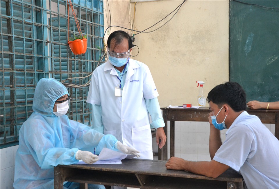 Ông NGuyễn Thanh Tùng (giữa) lắng nghe tư vấn của nữ tân bác sĩ tình nguyện với người tham gia tiêm vaccine. Ảnh: LT