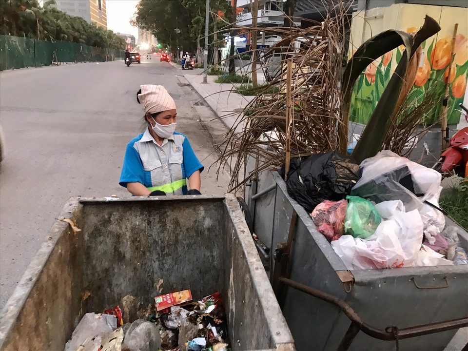 : Bà Vinh đang cật lực đẩy xe rác chất cao hơn đầu người trên đường Liễu Giai (quận Ba Đình, Hà Nội).