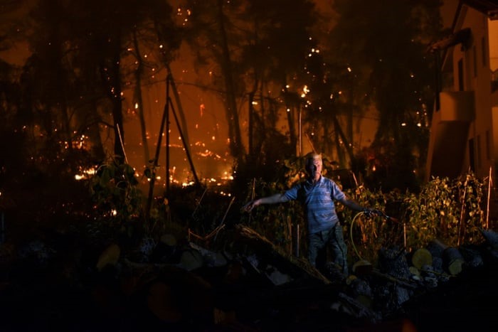 Một người đàn ông đang cố gắng dập tắt đám cháy rừng trên đảo Evia ở Hy Lạp. Ảnh chụp màn hình.