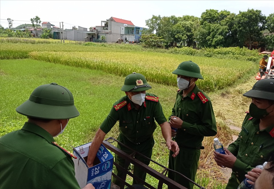 Tiếp tế nước uống cho các chiến sĩ công an xuống ruộng gặt lúa trong thời tiết nắng nóng.