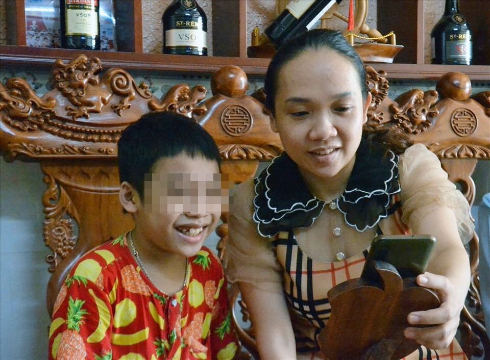Chị Nguyễn Thị Cẩm Huyền đang cùng con trai thao tác về giờ học online. Ảnh: LT