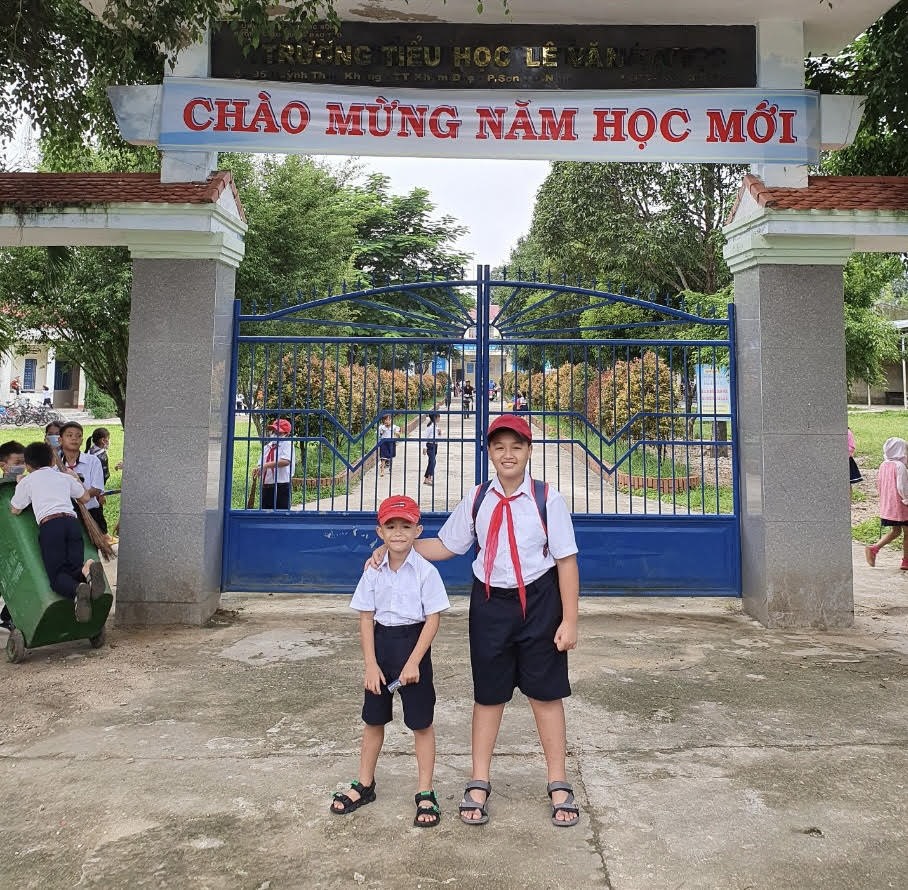 Hai con trai của anh Nguyễn Văn Nhạn trước cổng trường mới ở huyện miền núi Phước Sơn, tỉnh Quảng Nam. Ảnh: Tường Minh